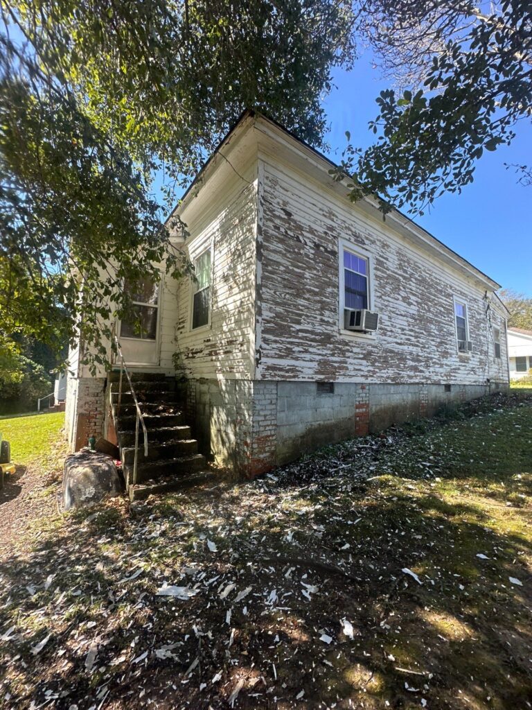 house washing is being done to remove peeling paint and debris from the exterior surfaces including the walls and steps