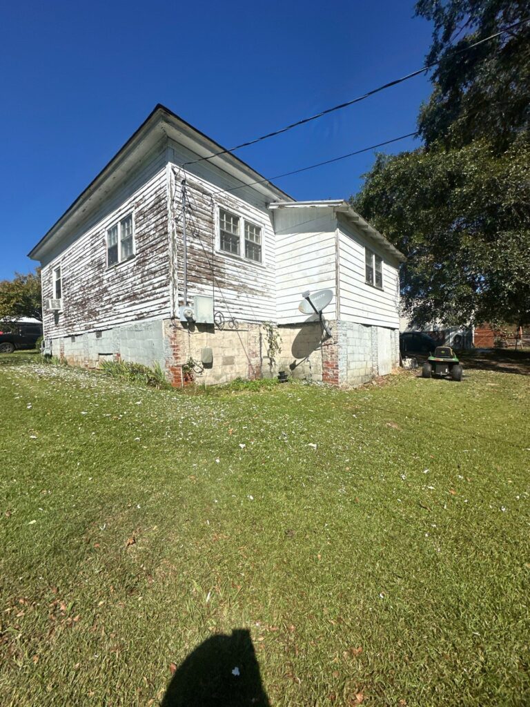 pressure washing is being done on the exterior siding and foundation of the house to remove dirt and grime