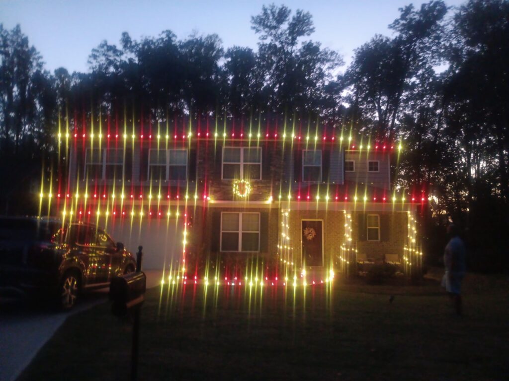 the photo shows festive lights being hung on a residential home for holiday decoration