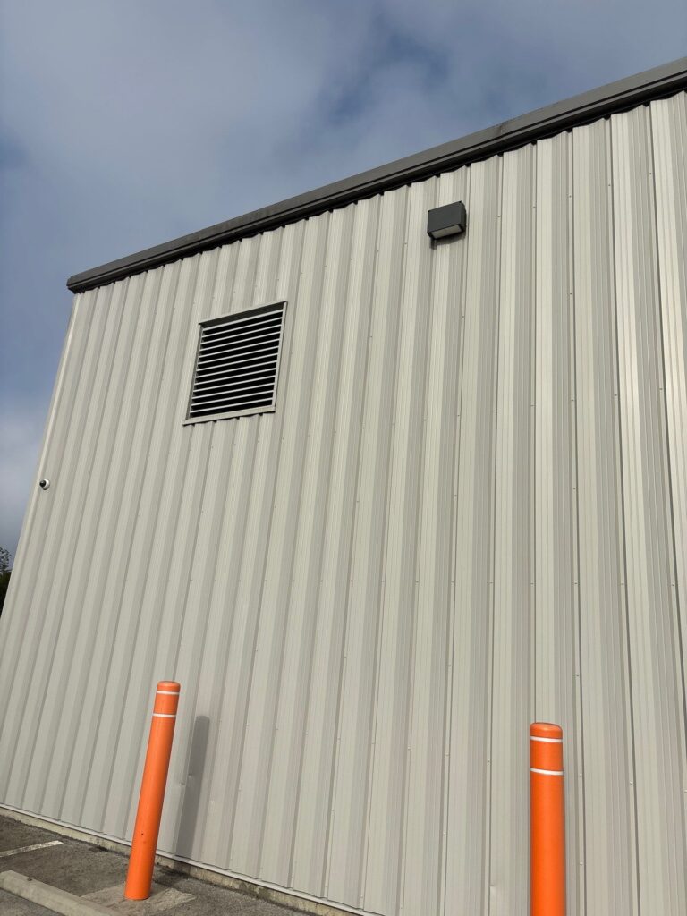 the service shown is cleaning the exterior metal siding of a building using pressure washing techniques