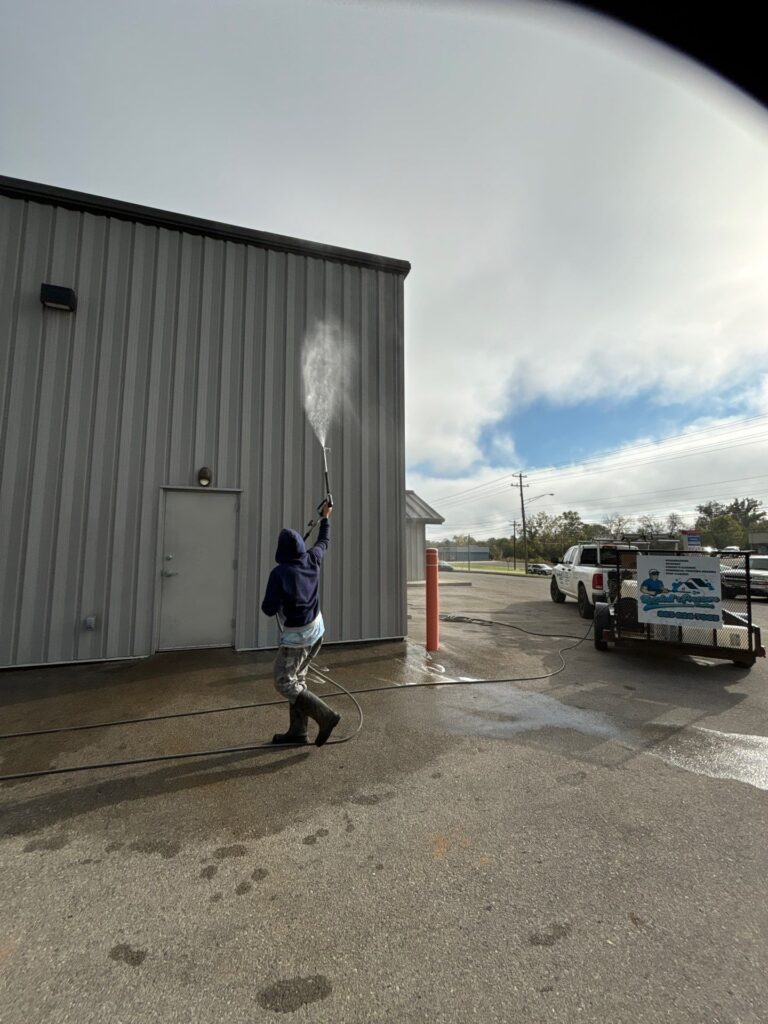 the service shown is pressure washing a metal building exterior and surrounding pavement surfaces to remove dirt and debris